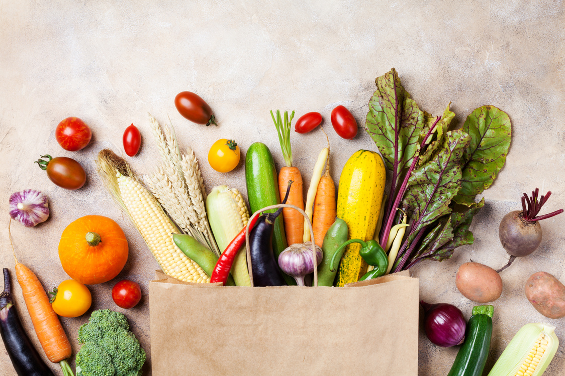 Autumn vegetables in shopping paper grocery bag on kitchen table top view.